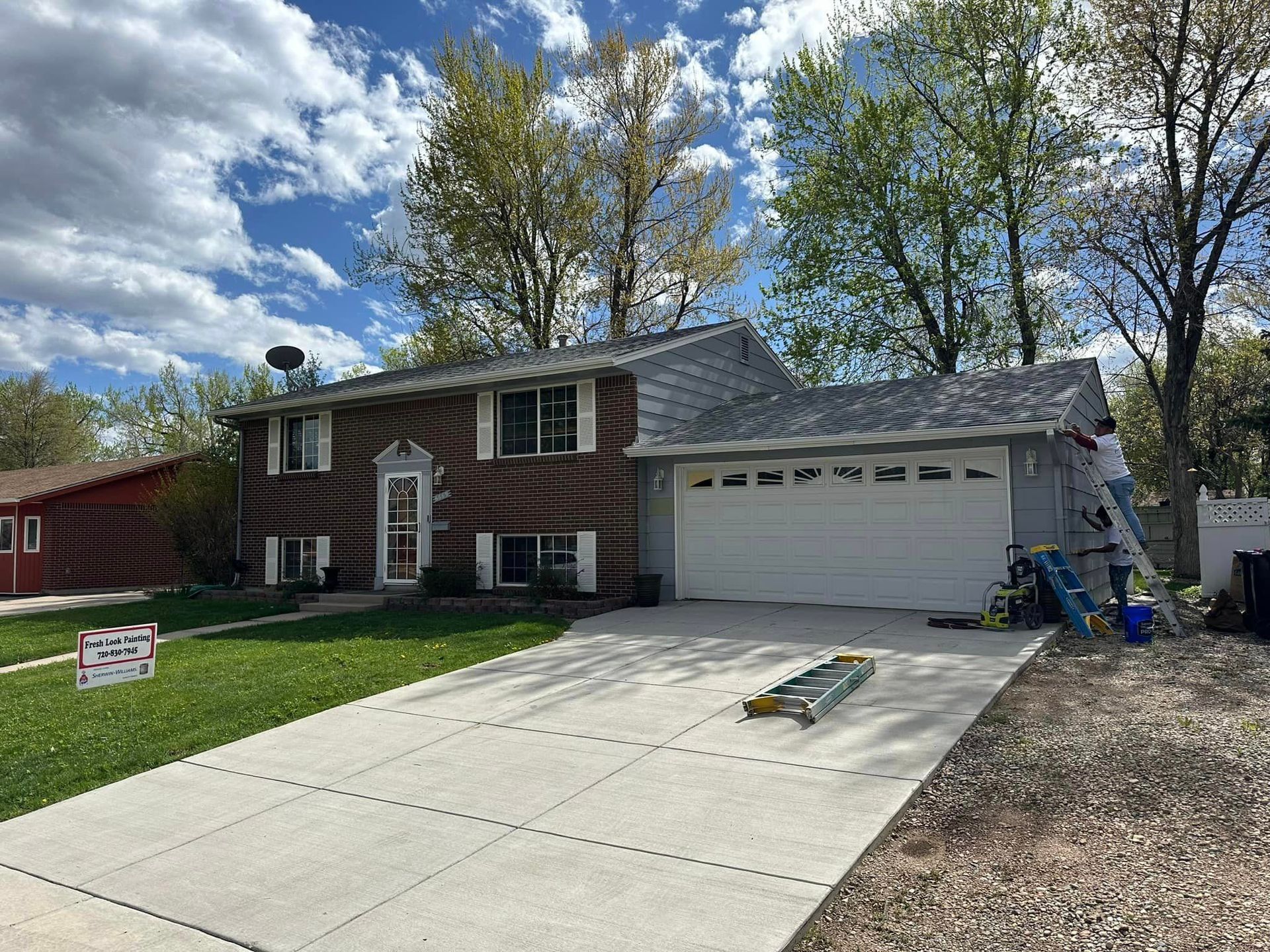 Two-story house with a newly shingled roof and a concrete driveway on a sunny day.