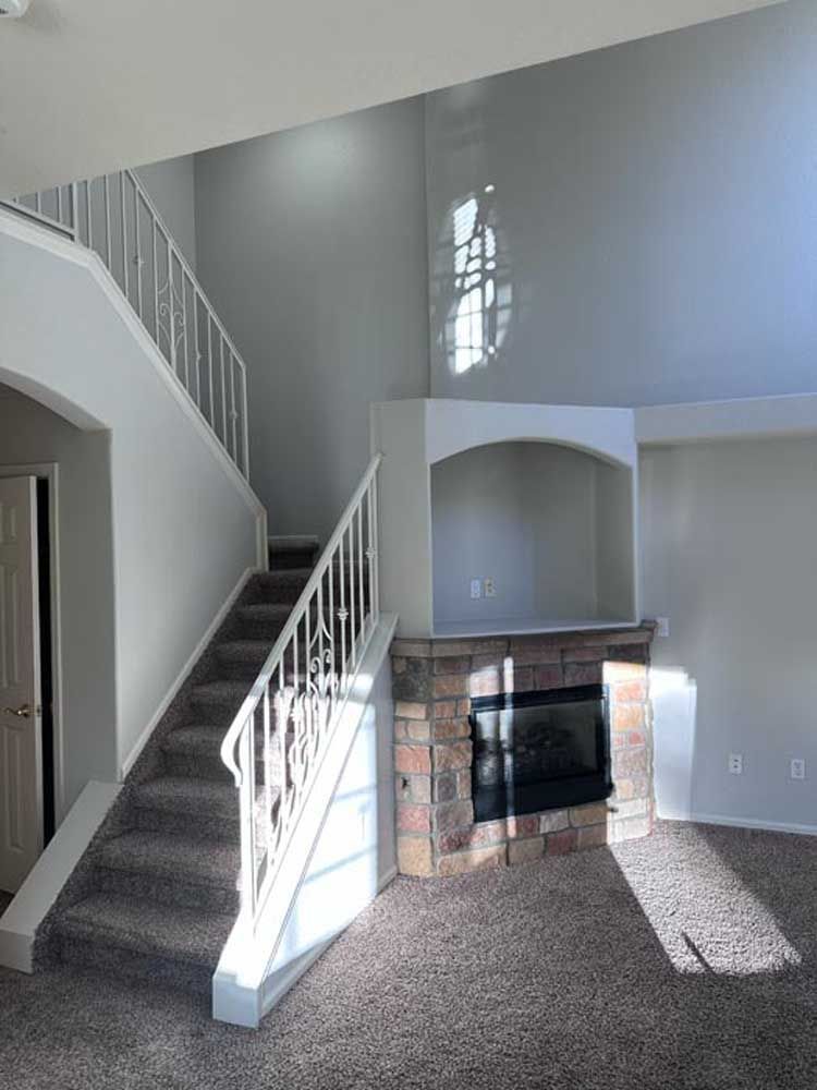 Interior view of a living room with a staircase, fireplace, and arched alcove.