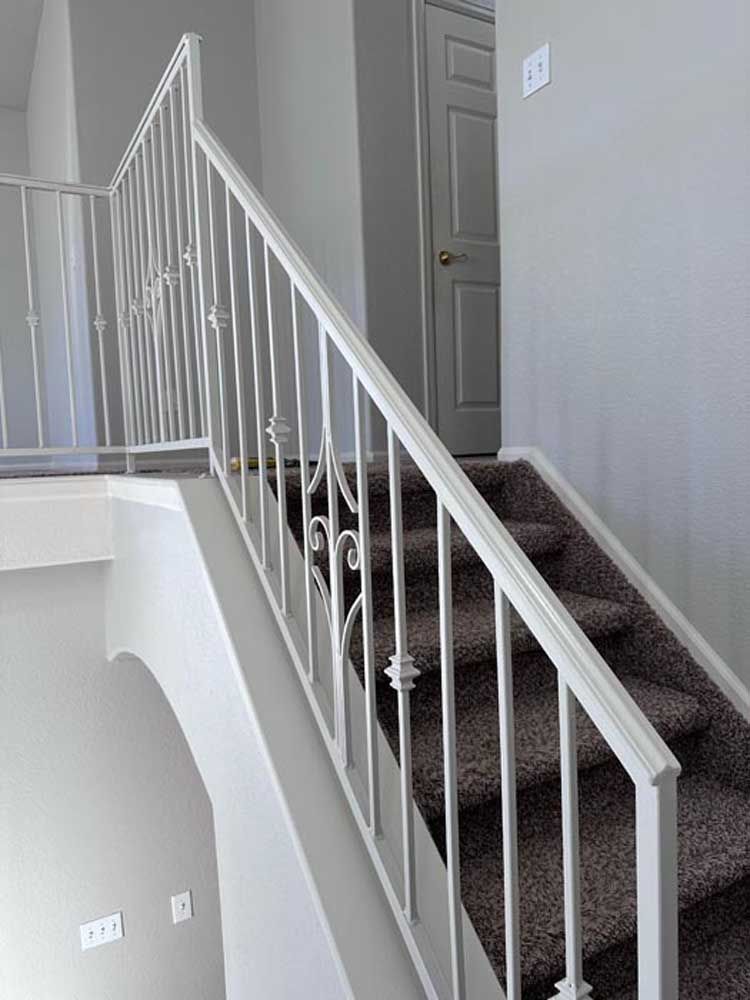 White stair railing and stairs with carpet leading to a door.