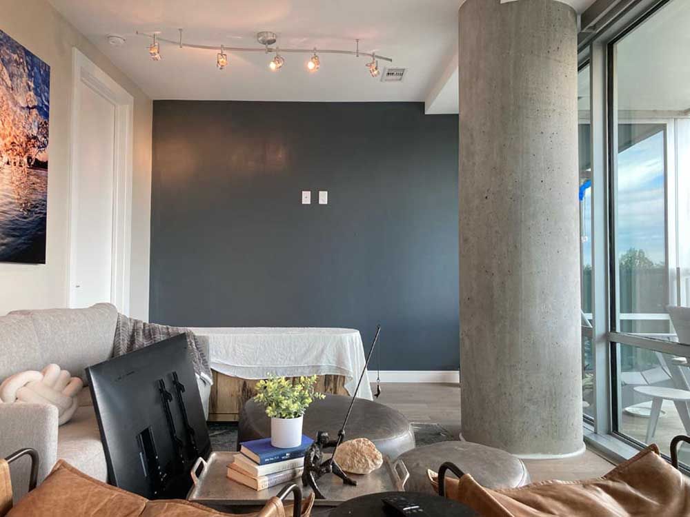 Living room with gray wall, concrete column, large window, sofa, and coffee table.