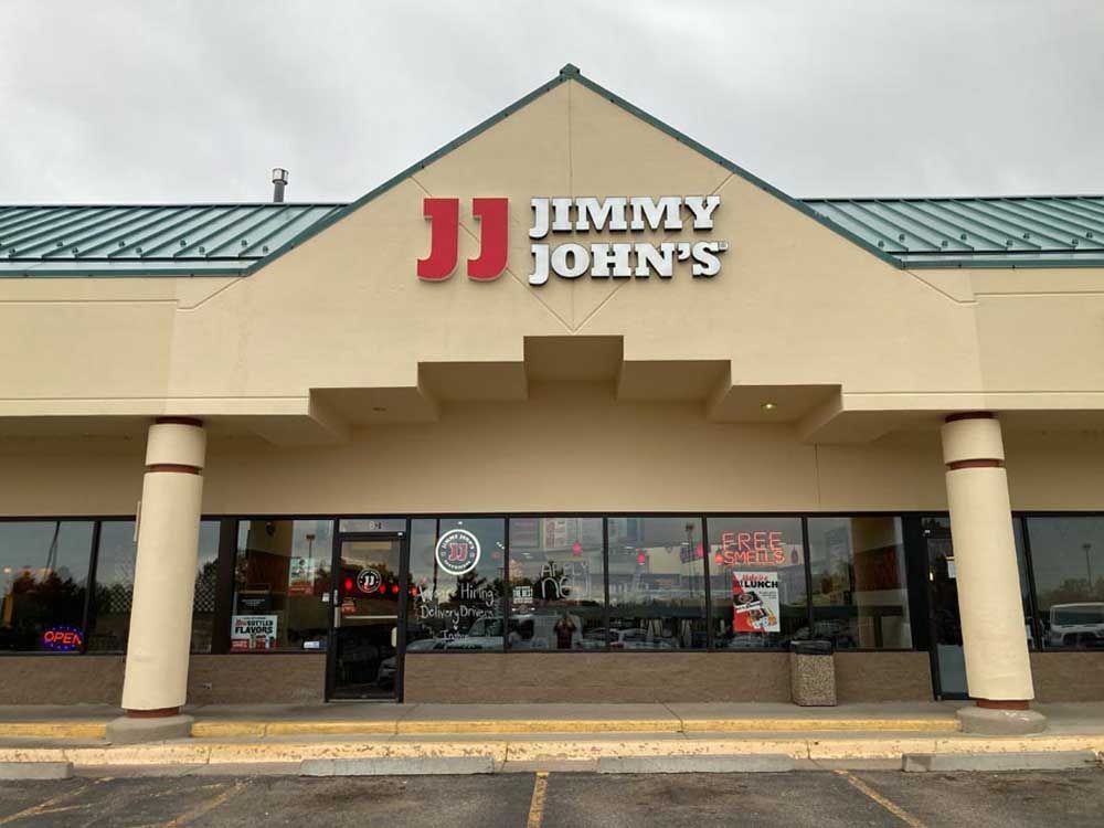 Jimmy John's sandwich shop exterior with the brand's logo above the entrance under a cloudy sky.