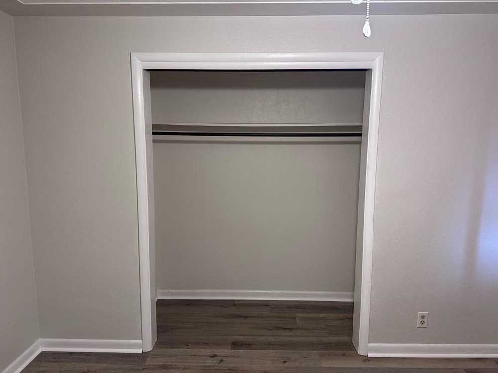 Empty closet with gray walls, white trim, and a clothing rod.