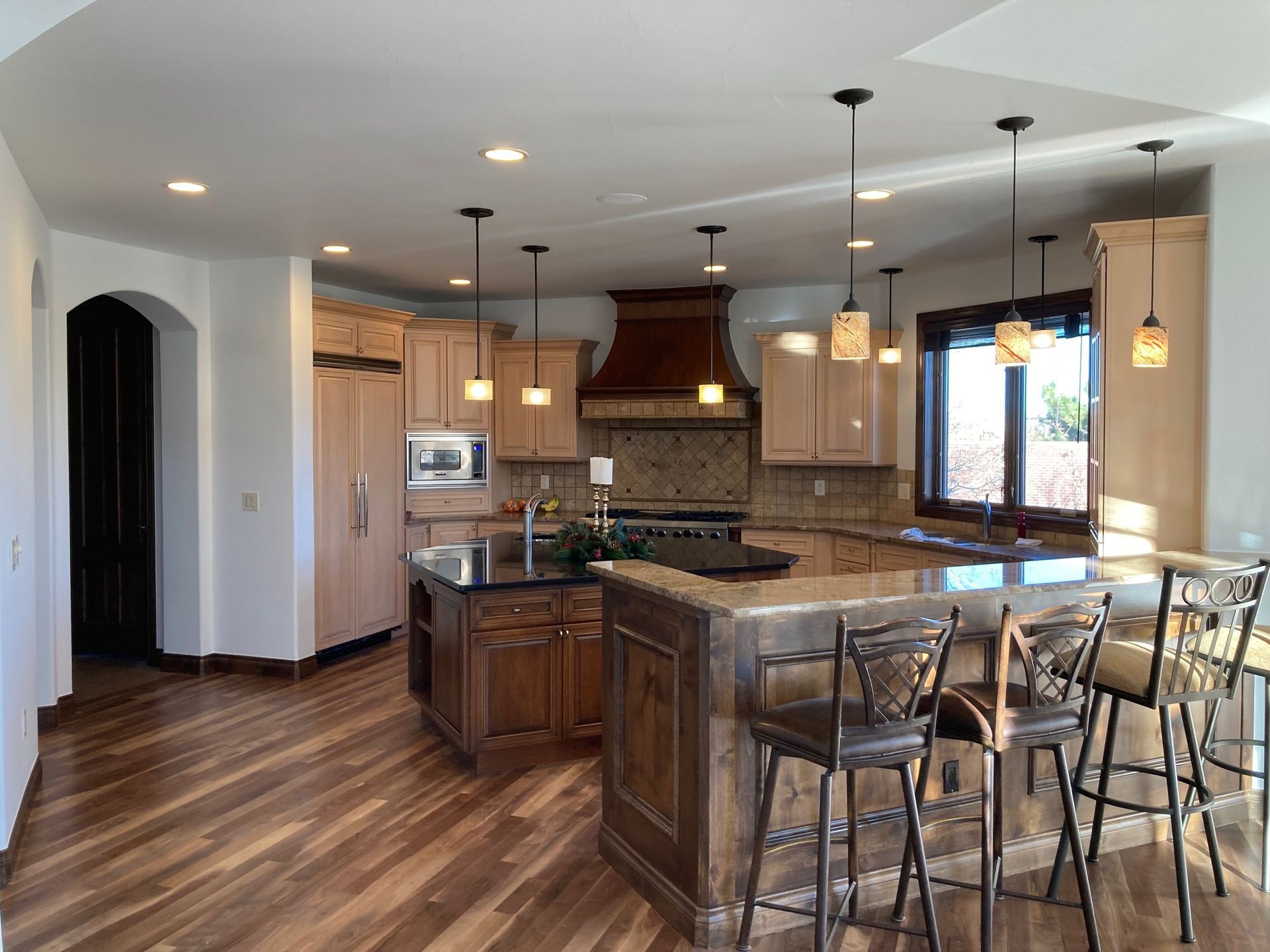 Spacious kitchen with wood cabinets, island, and bar seating; hardwood floors, recessed lighting.
