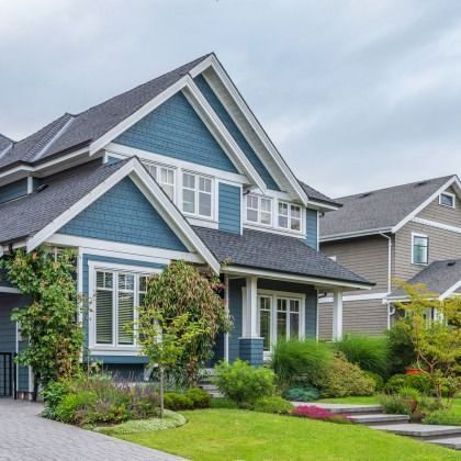 Blue and white house with a dark roof and manicured lawn.