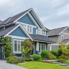 Blue and white house with a dark roof and manicured lawn.