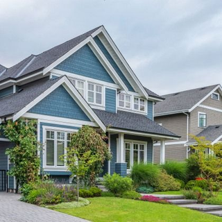 Blue and white house with a dark roof and manicured lawn.