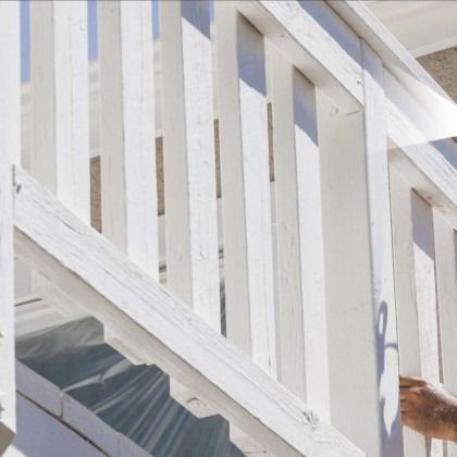 White painted wooden railing on steps, bright sunlight.