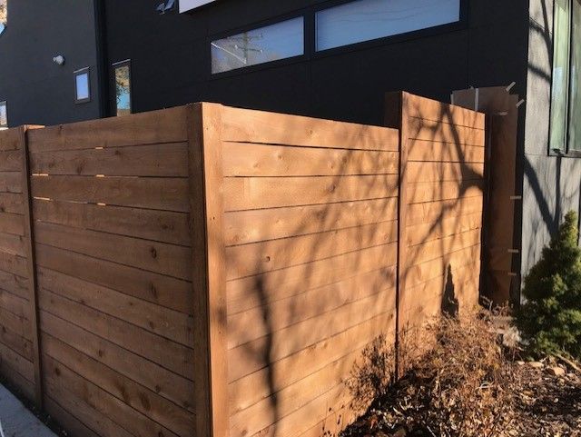 Wooden privacy fence, brown stained, surrounds a residential property.