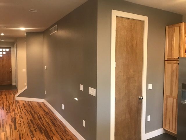 Interior view of hallway with gray walls, wooden floor, and a door with white trim.