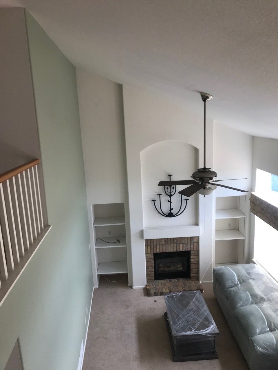 High-angle view of a living room with a fireplace, bookshelves, a sofa, and a ceiling fan.