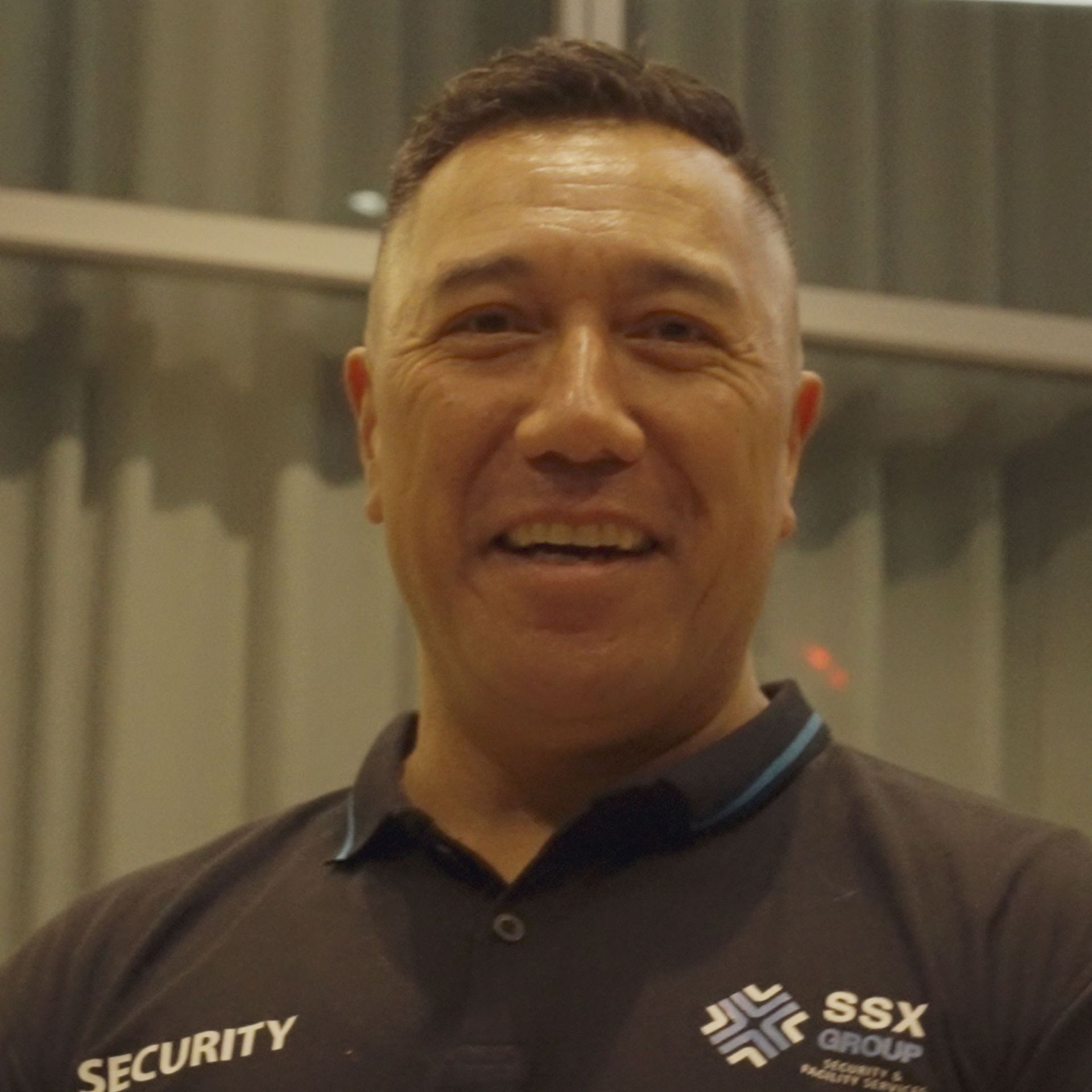 A man wearing a ssx security shirt smiles for the camera