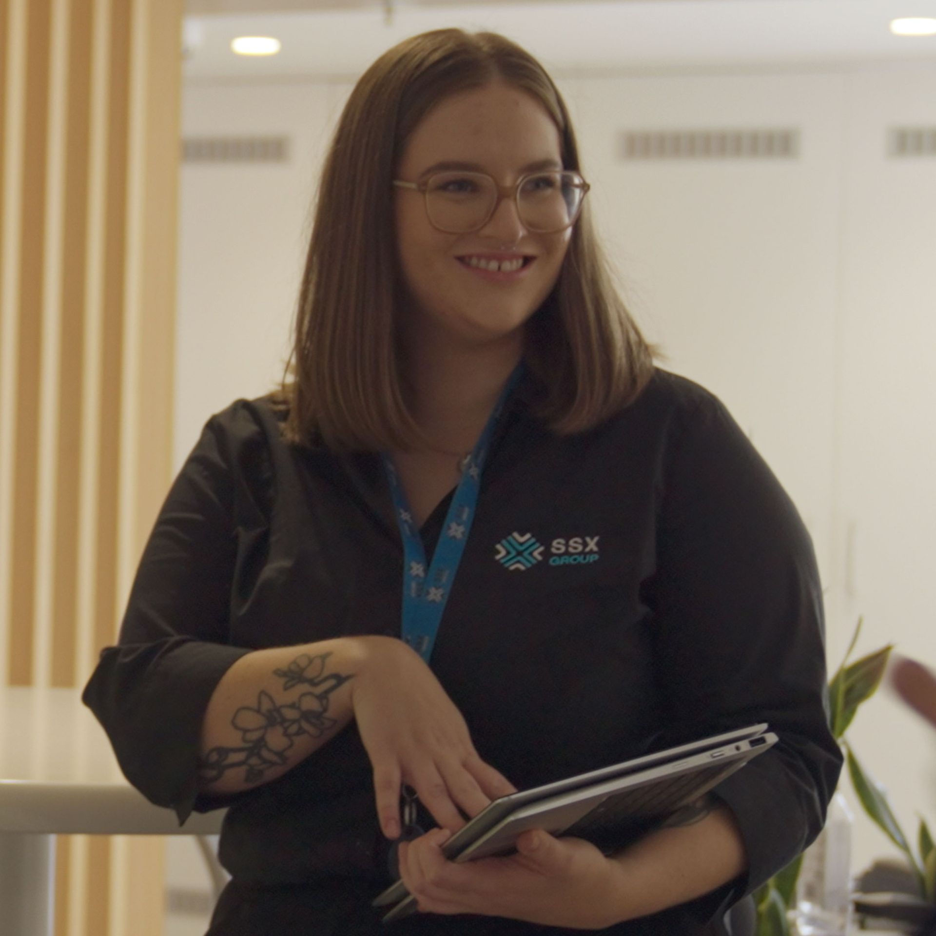 A woman wearing glasses and a black shirt that says sgx