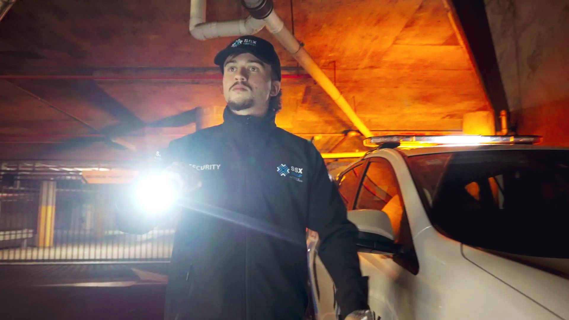 A man is standing next to a car in a parking garage.