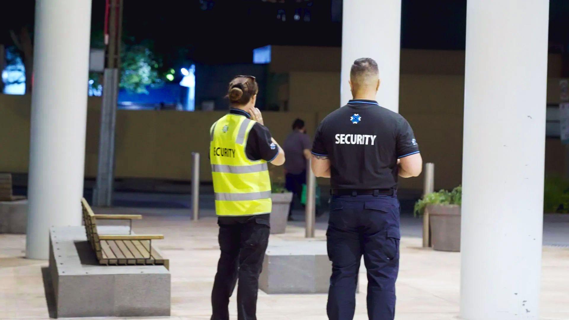 Two security guards are standing next to each other in front of a building.