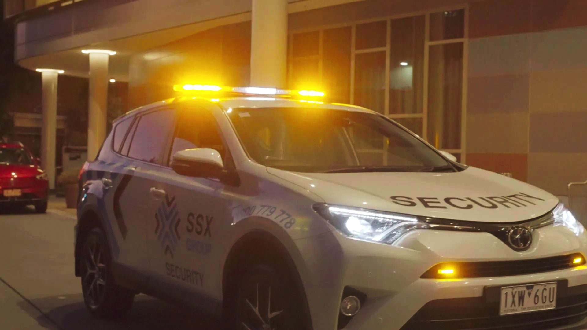 A white car with yellow lights on top of it is parked in front of a building.