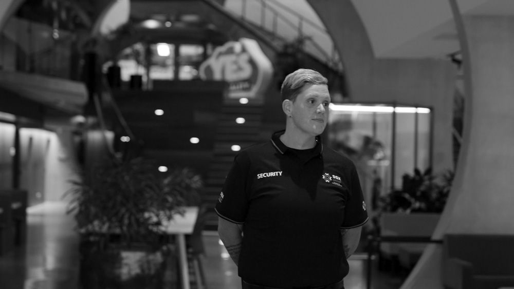 A black and white photo of a man standing in front of a building.