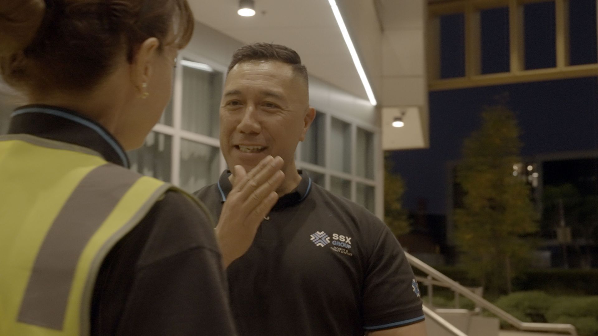 A man and a woman are talking to each other in front of a building.