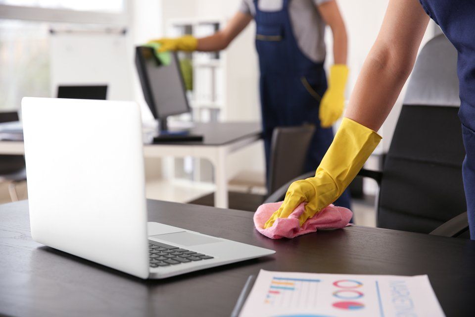 Cleaner Wiping Down Office Desk — Cleaning Services in Airlie Beach, QLD