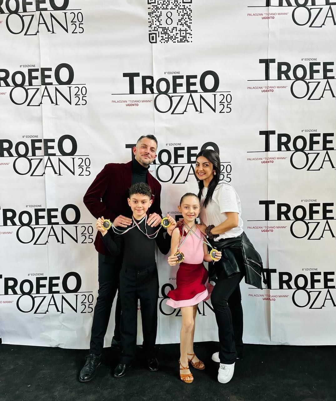 Una famiglia di quattro persone è in piedi davanti a uno sfondo con la scritta 