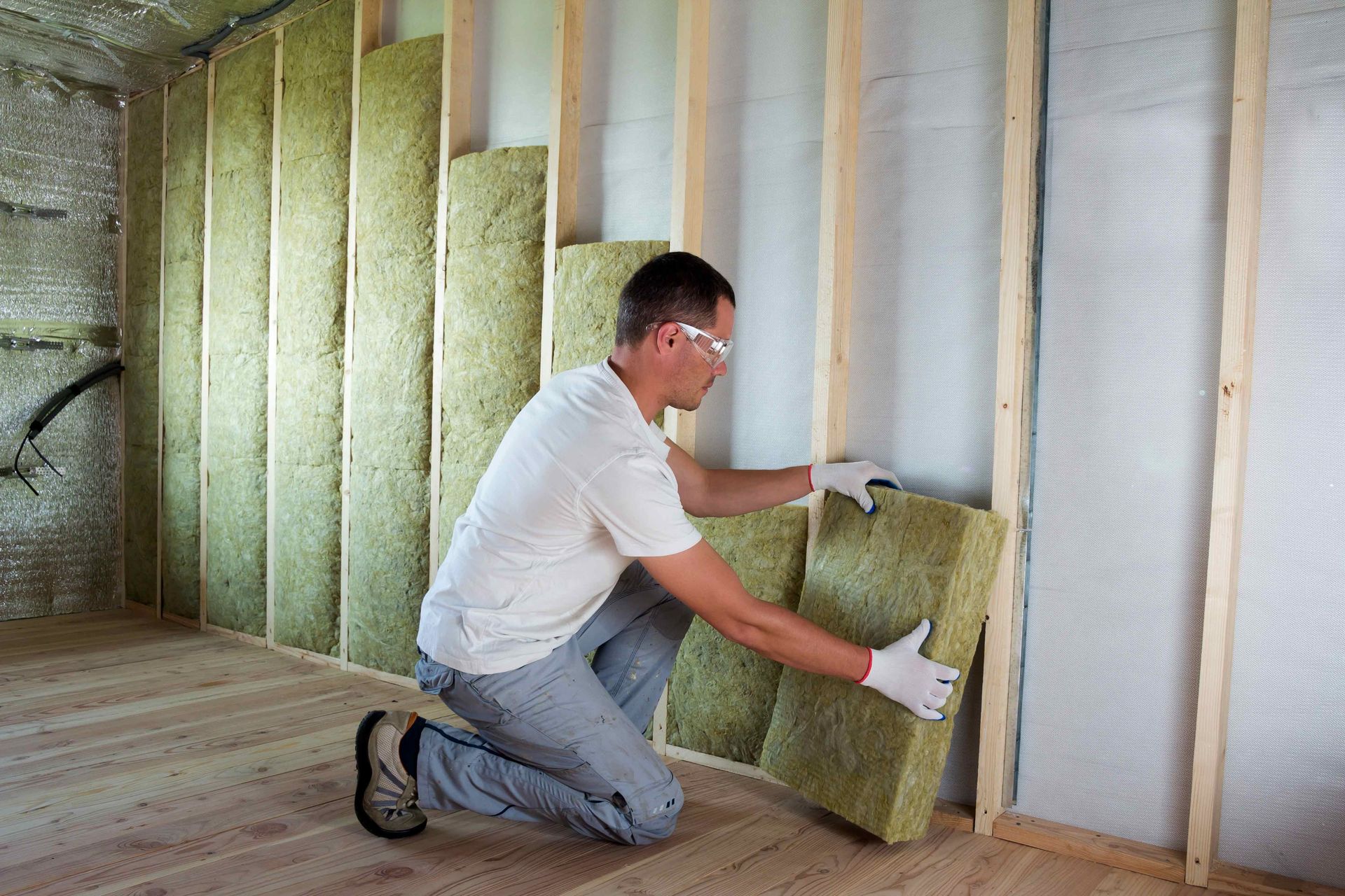 A man is installing insulation on a wall in a room.