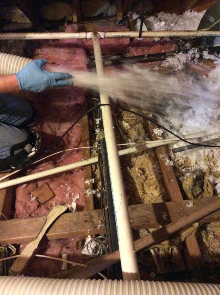 A person is blowing insulation into an attic with a vacuum.