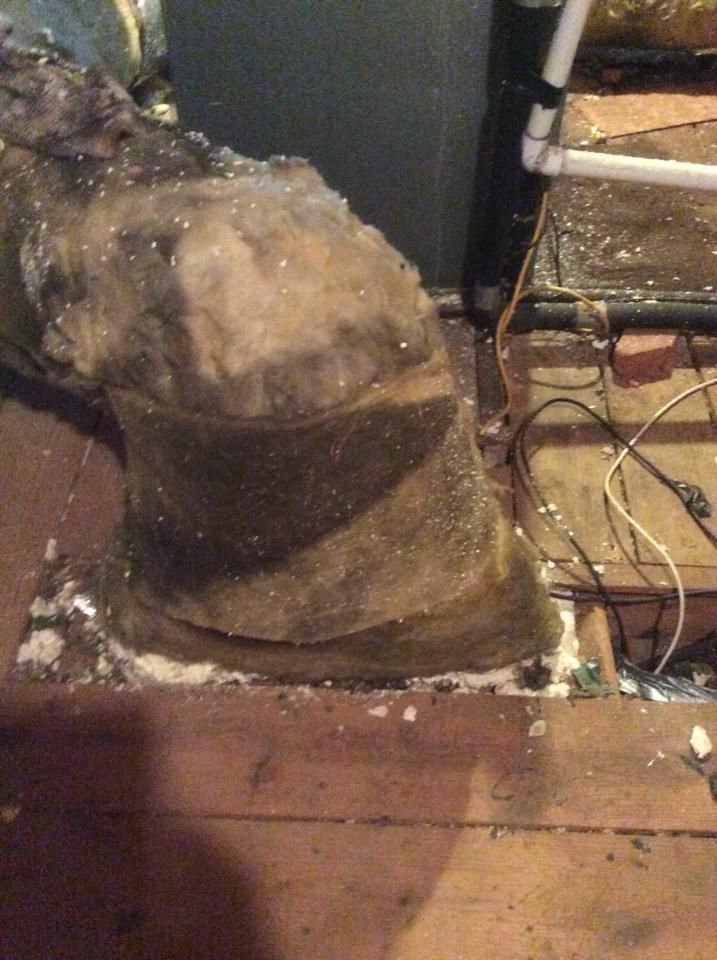 A large rock is sitting on a wooden floor next to a pipe.