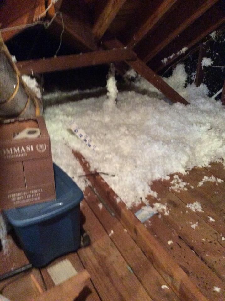 There is a box on top of a blue bin in the attic.