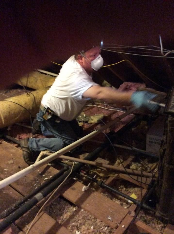 A man wearing a mask is working in an attic.