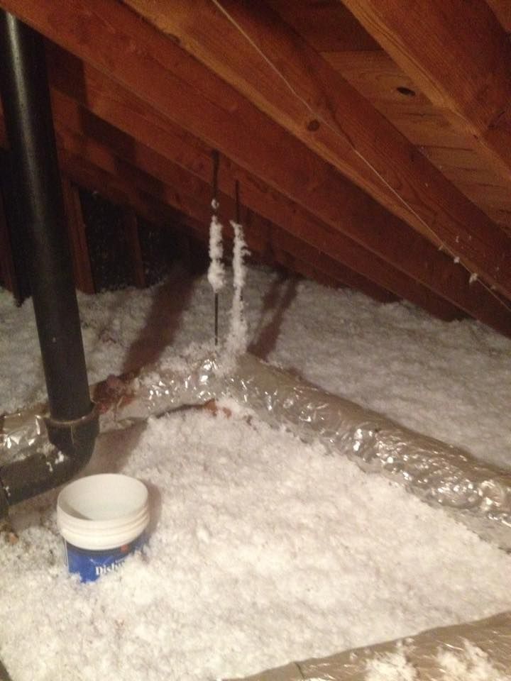 An attic with a lot of insulation and pipes.