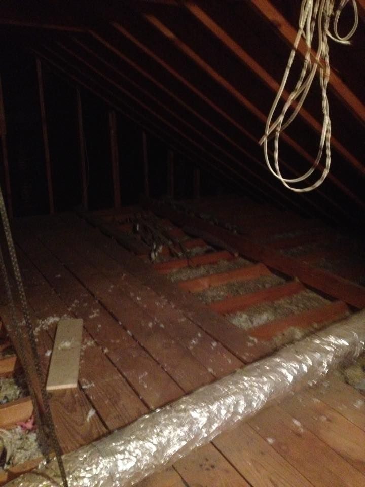 A rope is hanging from the ceiling of an attic.