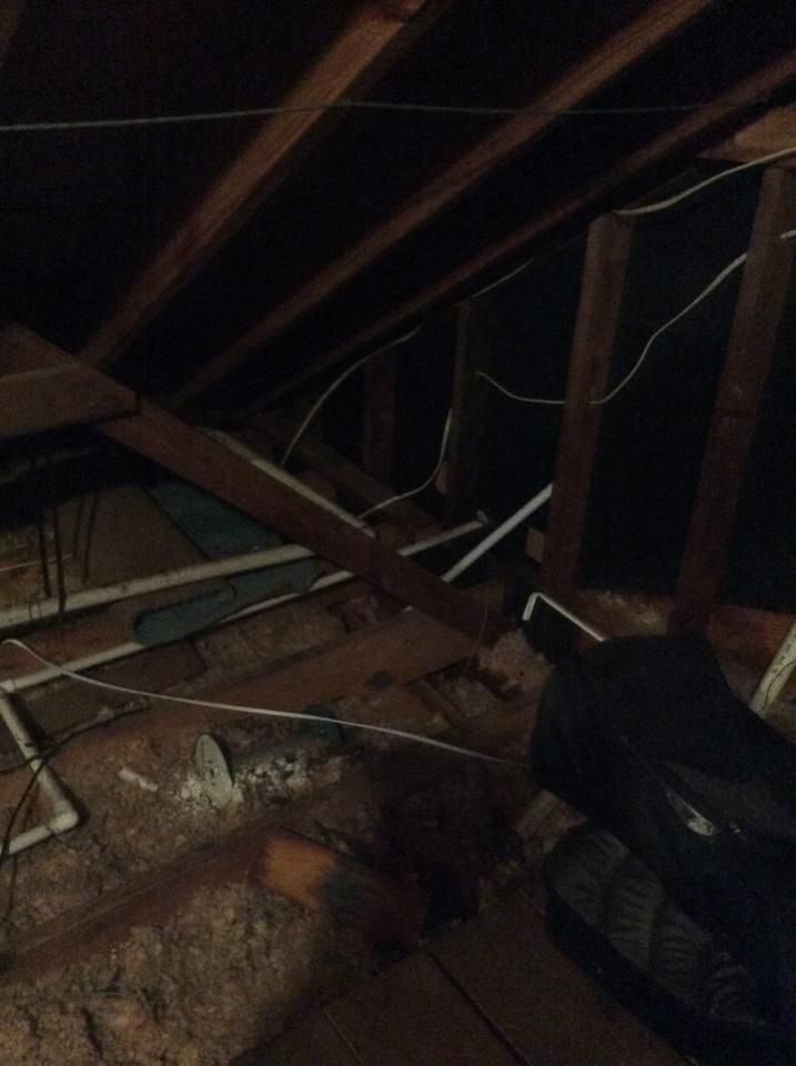 A dark attic with a lot of wires hanging from the ceiling.