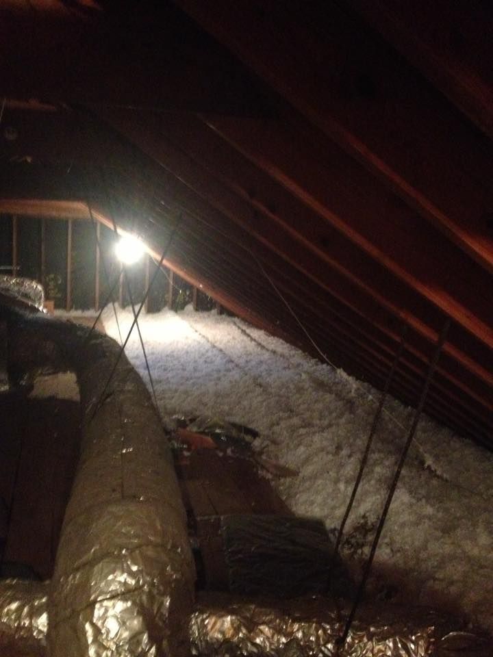 An attic with a lot of insulation and a light on the ceiling.