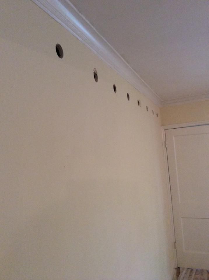 A white wall with holes in it and a door in a room.