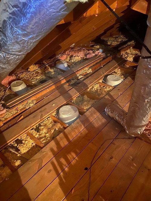 A person is working on a wooden floor in an attic.