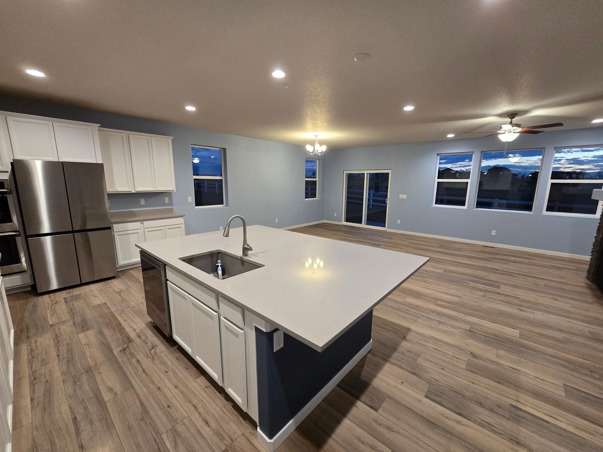 Modern kitchen with island, stainless steel appliances, white cabinets, and wood flooring.