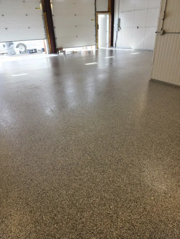 Polished concrete floor in an empty, well-lit industrial space with open bay doors.