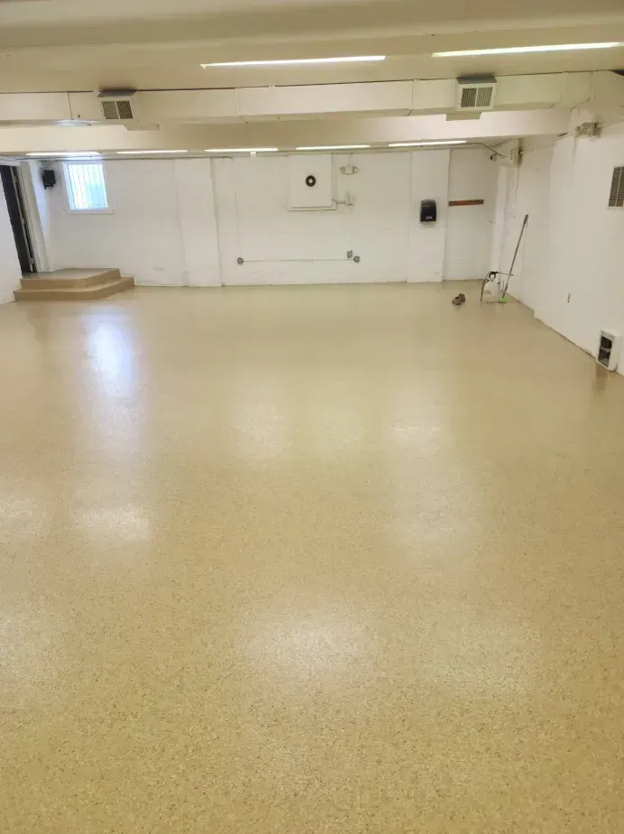 Empty room with beige floor and white walls. Small set of steps in the corner.