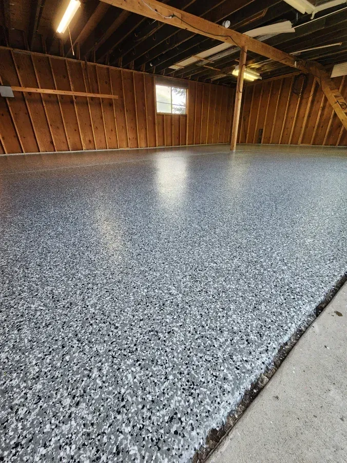 Garage with a speckled gray epoxy floor, wood walls, and a small window.