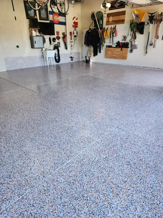 Garage with epoxy-coated floor. Walls have tools, flags, and other items hanging.
