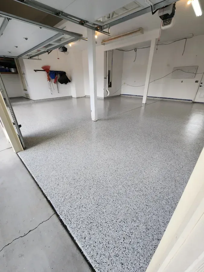 Garage with a gray speckled epoxy floor and white walls.