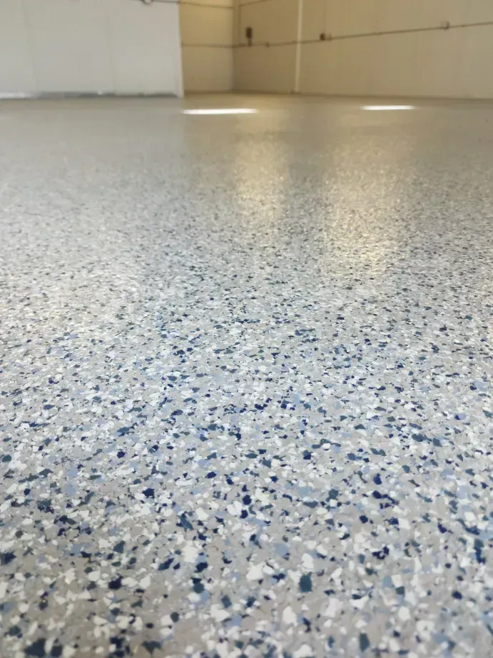 Close-up of a speckled epoxy floor with shades of blue, gray, and white in an empty room.