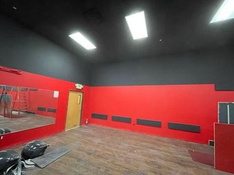 Interior of a room with red walls and a black ceiling. A large mirror and a door are visible.