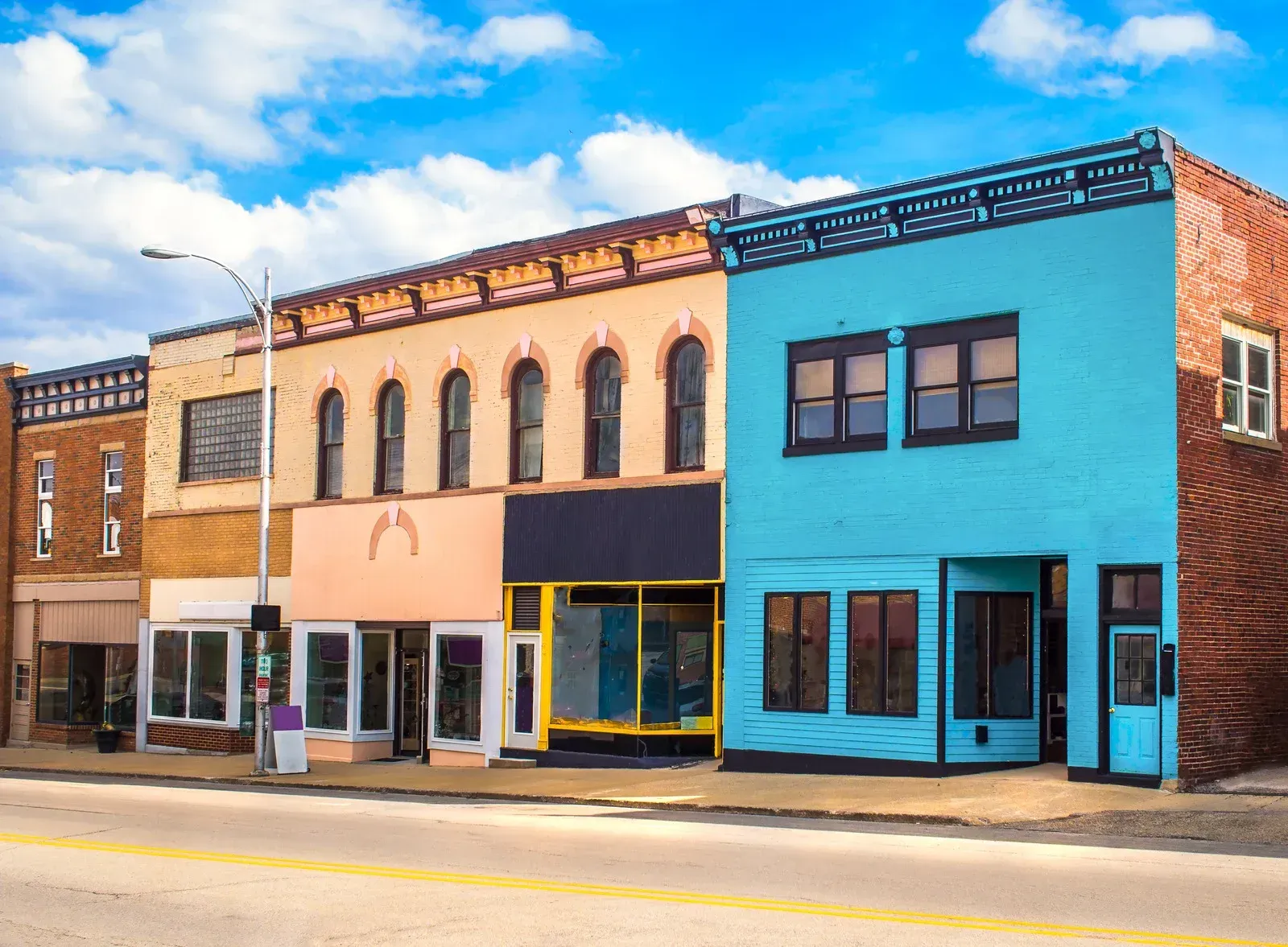 Row of colorful commercial buildings along a street with blue sky.
