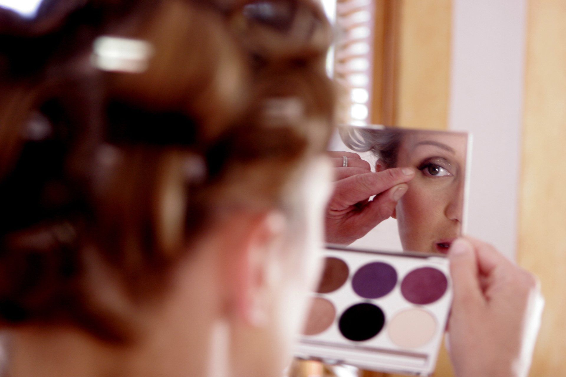A woman is applying makeup in front of a mirror