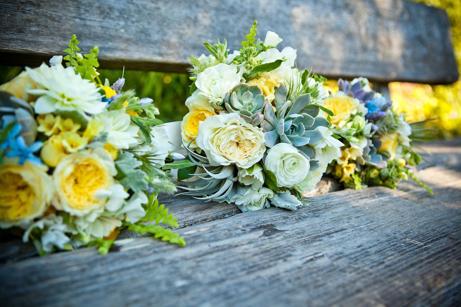 A bunch of flowers are sitting on a wooden bench.