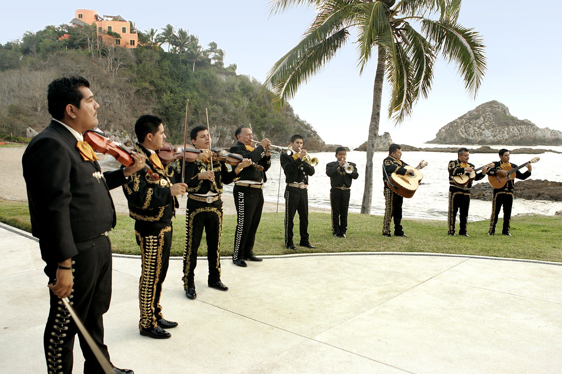 A group of mariachi players are standing in front of a beach