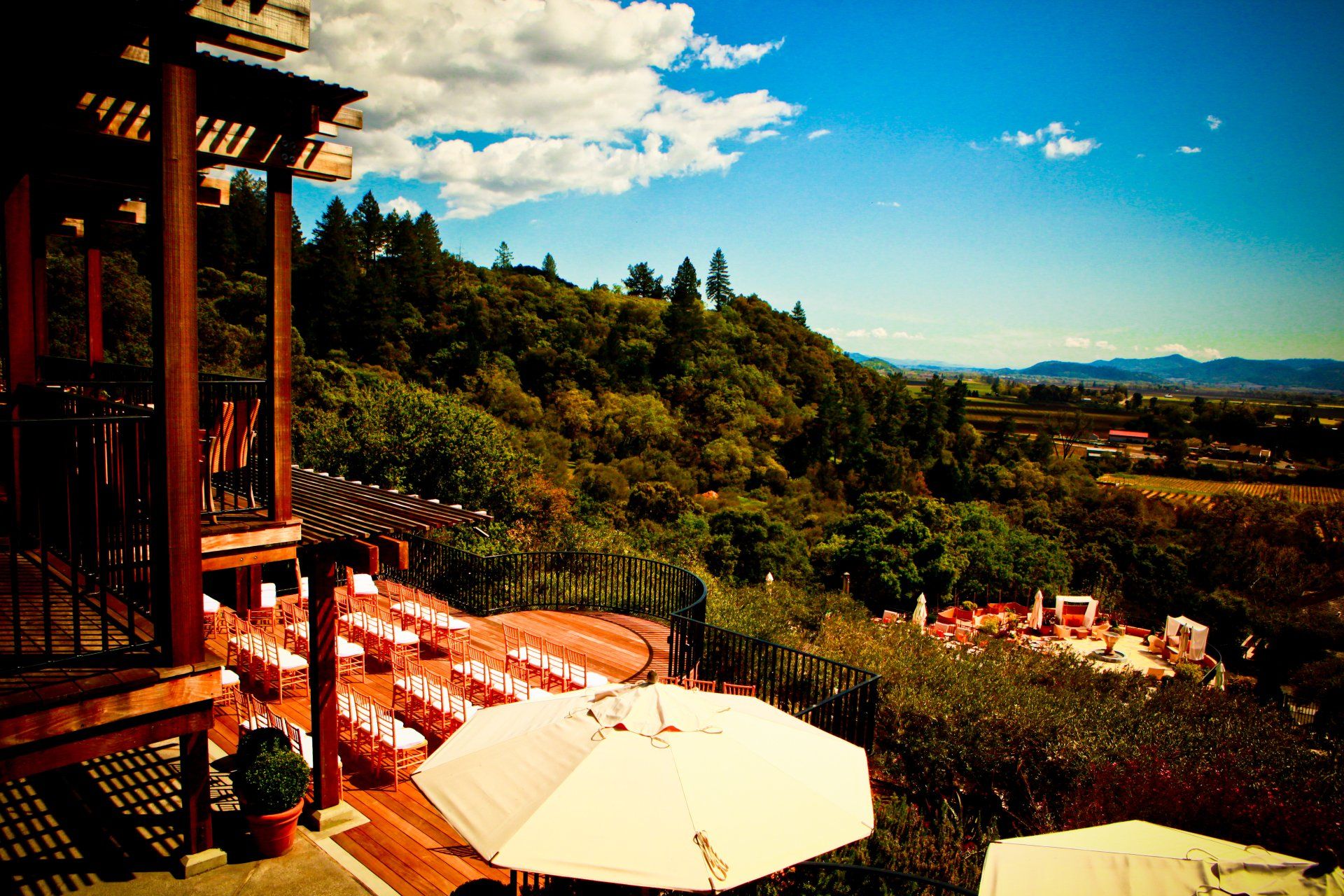 A row of tables and umbrellas on a deck overlooking a forest