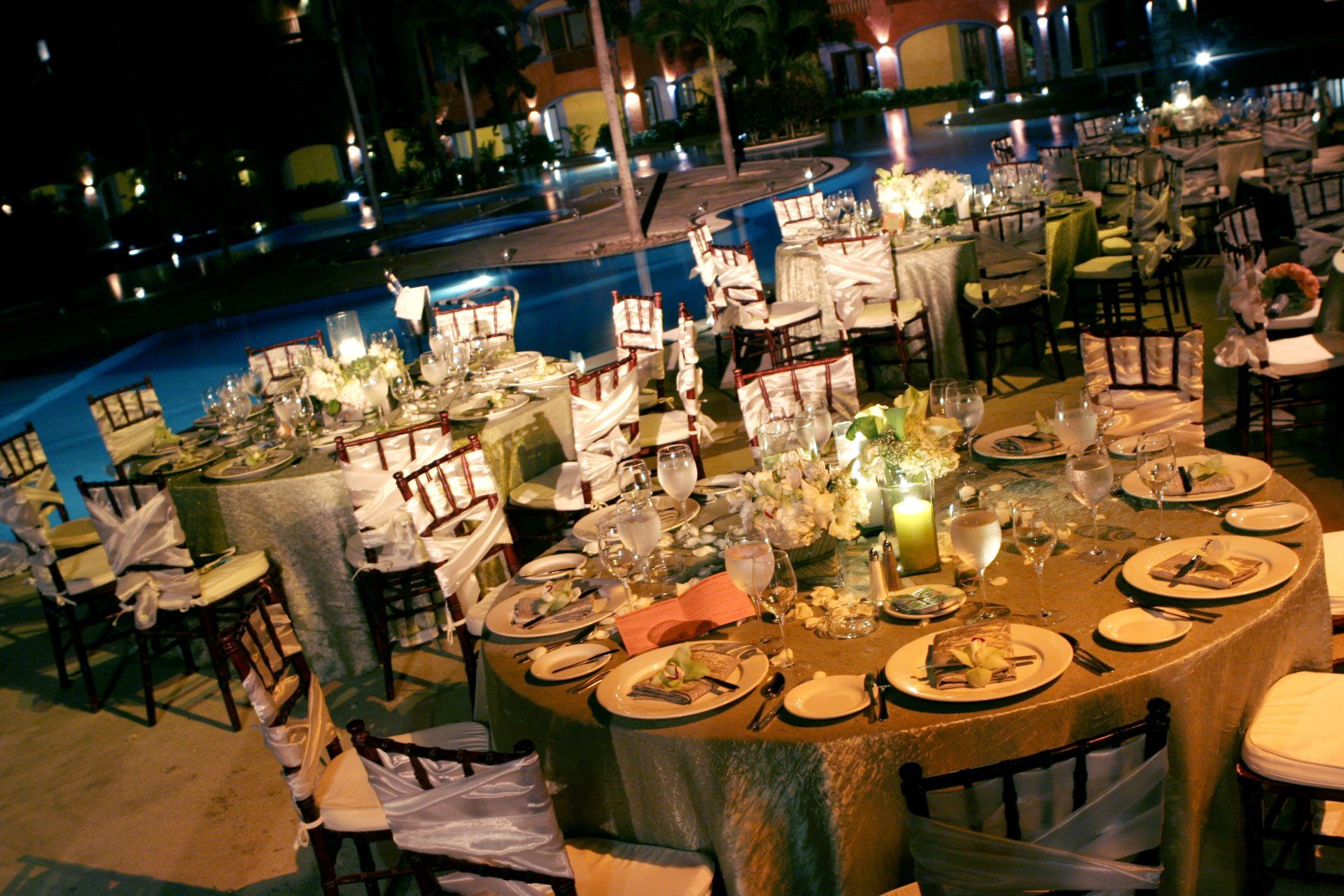 A table set for a wedding reception with a pool in the background