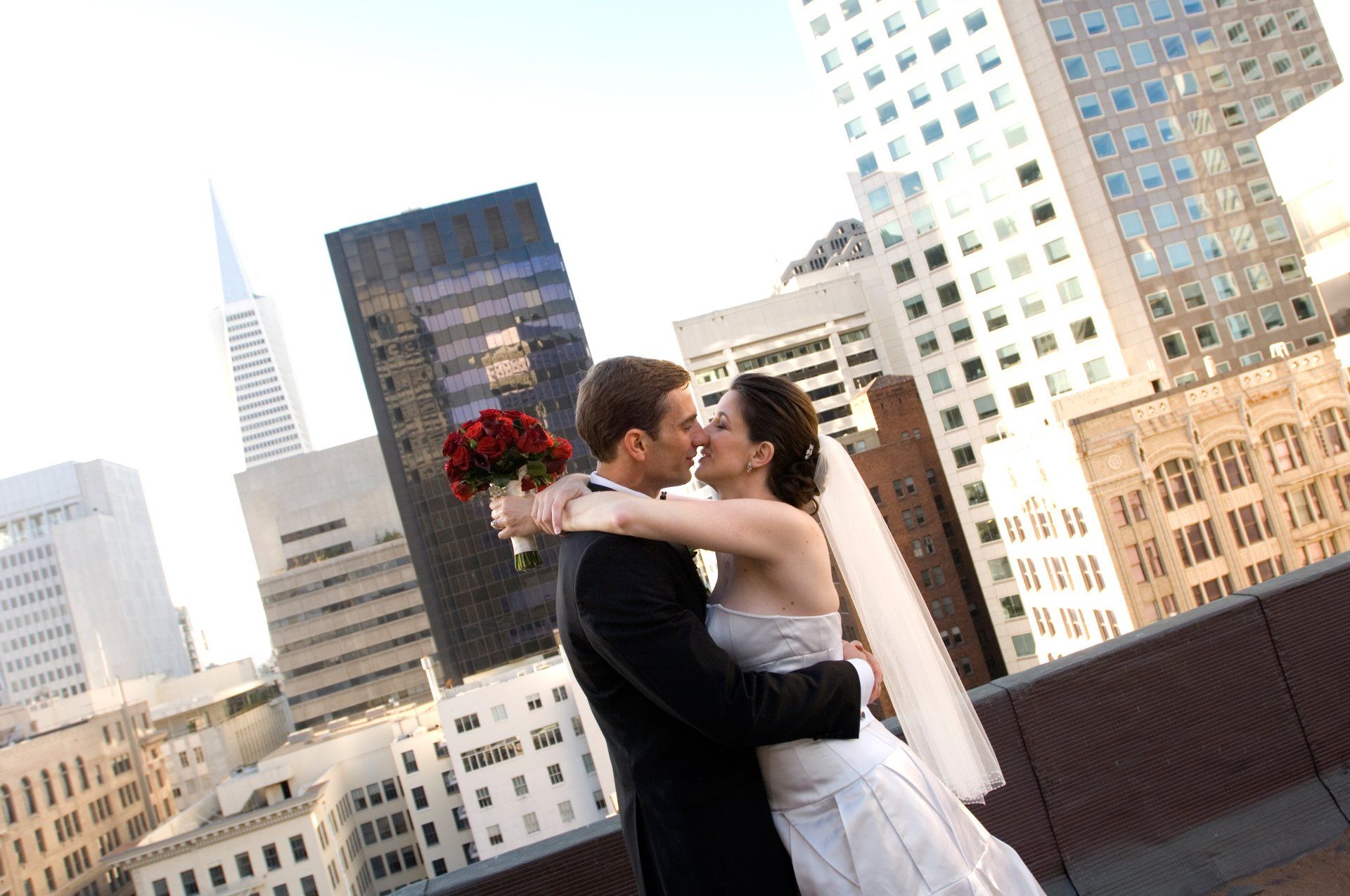 A bride and groom kissing in front of a city skyline