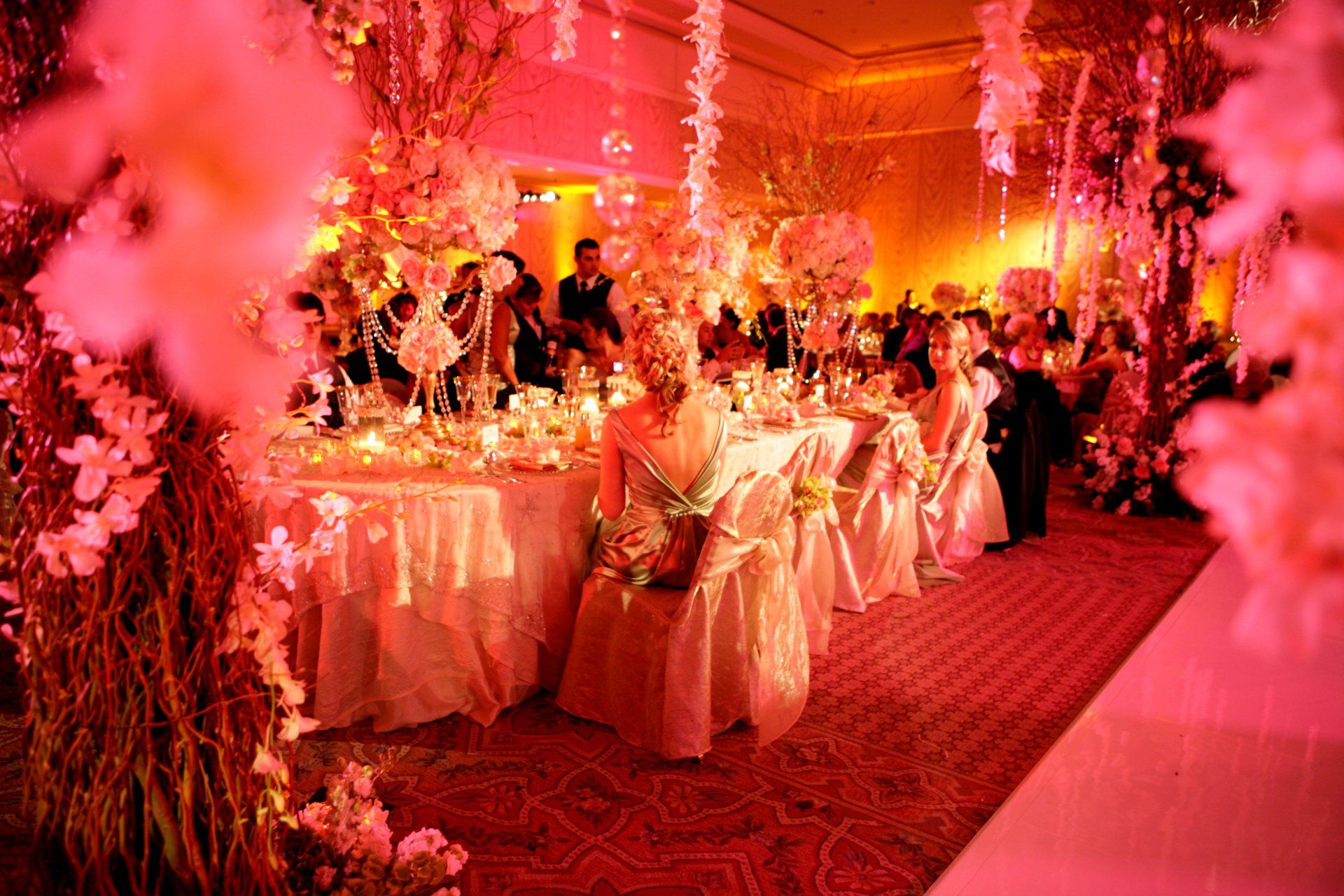 A large room filled with tables and chairs decorated with pink flowers.